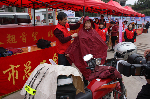 梧州市總工會(huì)的黨員義工們?cè)谑袞|出口春運(yùn)服務(wù)站助力&ldquo;摩托大軍&rdquo;平安返鄉(xiāng)，幫助他們檢查車輛和行李，穿上雨衣。--黃賀峰攝.j